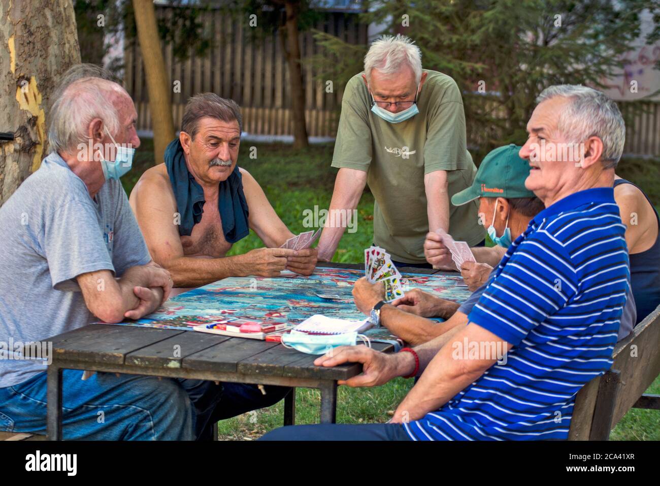 Zrenjanin, Serbia, 29 luglio 2020. I signori più anziani e i pensionati giocano le carte ogni giorno all'ombra di un grande albero. Ci sono sempre osservatori curiosi Foto Stock