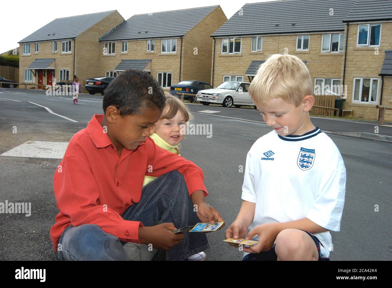 Tre bambini che giocano con le carte commerciali nella loro proprietà dell'associazione di alloggiamento; Halifax; Yorkshire UK Foto Stock