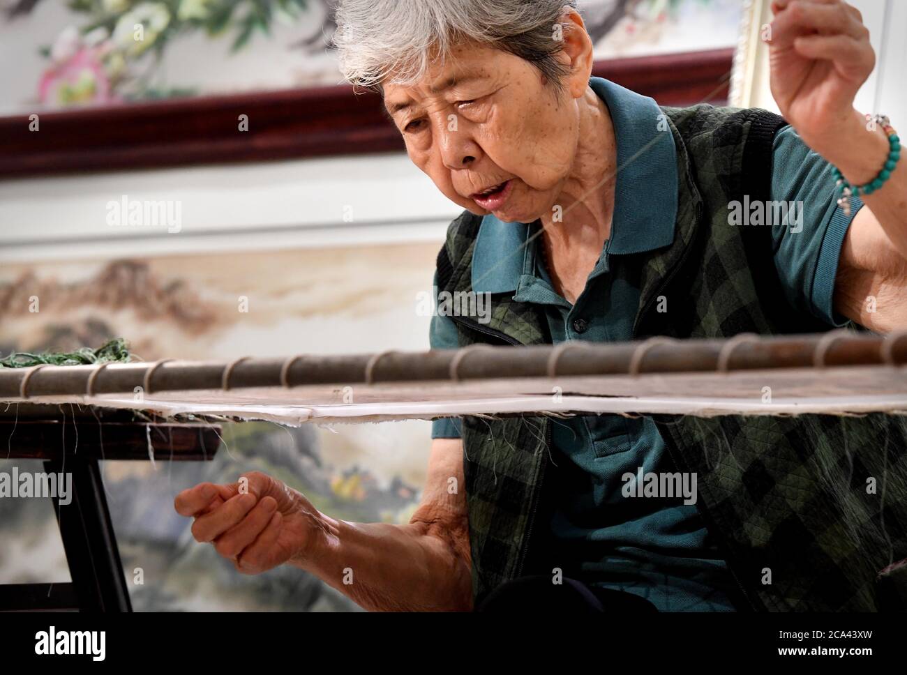 (200804) -- ZHENGZHOU, 4 agosto 2020 (Xinhua) -- Wang Suhua fa ricamo biano alla sua azienda nella città di Kaifeng, nella provincia di Henan della Cina centrale, 30 luglio 2020. Wang Suhua, 85, un patrimonio culturale immateriale a livello nazionale ereditatore di ricami biani, sta facendo il lavoro dal 1957. Raccogliendo antiche opere di ricamo e ordinando le tradizionali capacità di ricamo nella dinastia Song, Wang e i suoi compagni di lavoro crearono più di dieci nuovi modi di cucire, e con successo fecero un capolavoro di ricamo biano del famoso dipinto antico 'lungo il fiume durante il Festival Qingming' nel 1959. Foto Stock