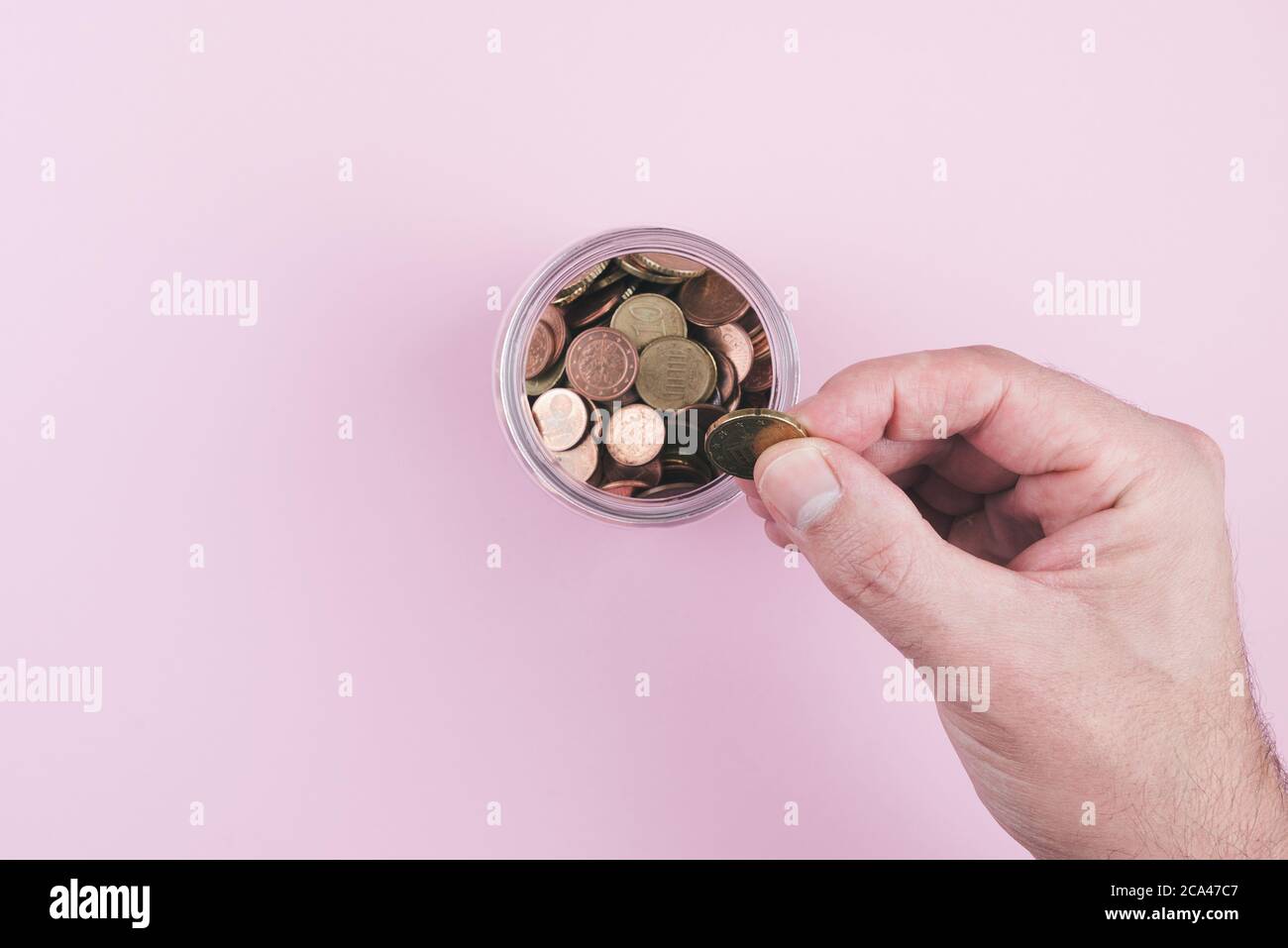 sopra la vista della mano che mette la moneta in vaso riempito con piccolo cambiamento Foto Stock