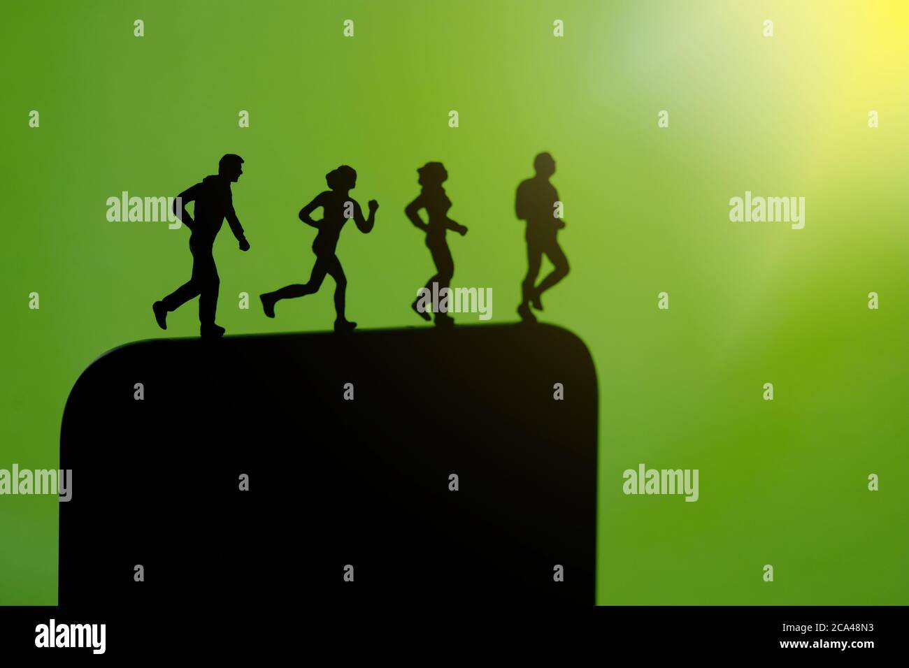 Concetto di app per il monitoraggio della corsa e del jogging. Una famiglia che opera sopra lo smartphone. Fotografia di figure di persone in miniatura. Foto Stock