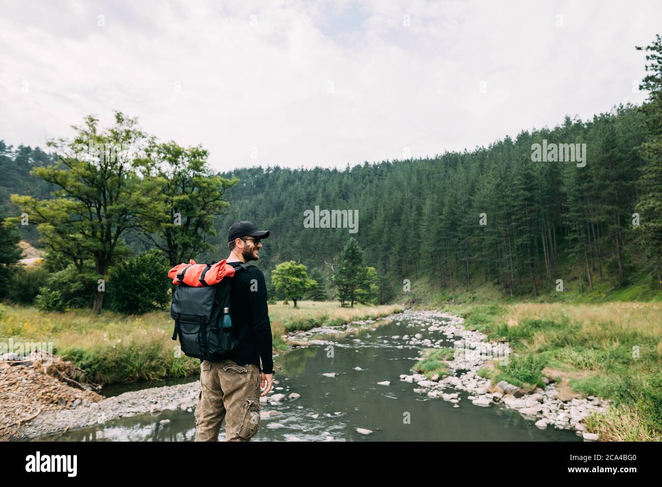Giovane uomo natura esploratore godendo la vista del fiume nella natura selvaggia Foto Stock