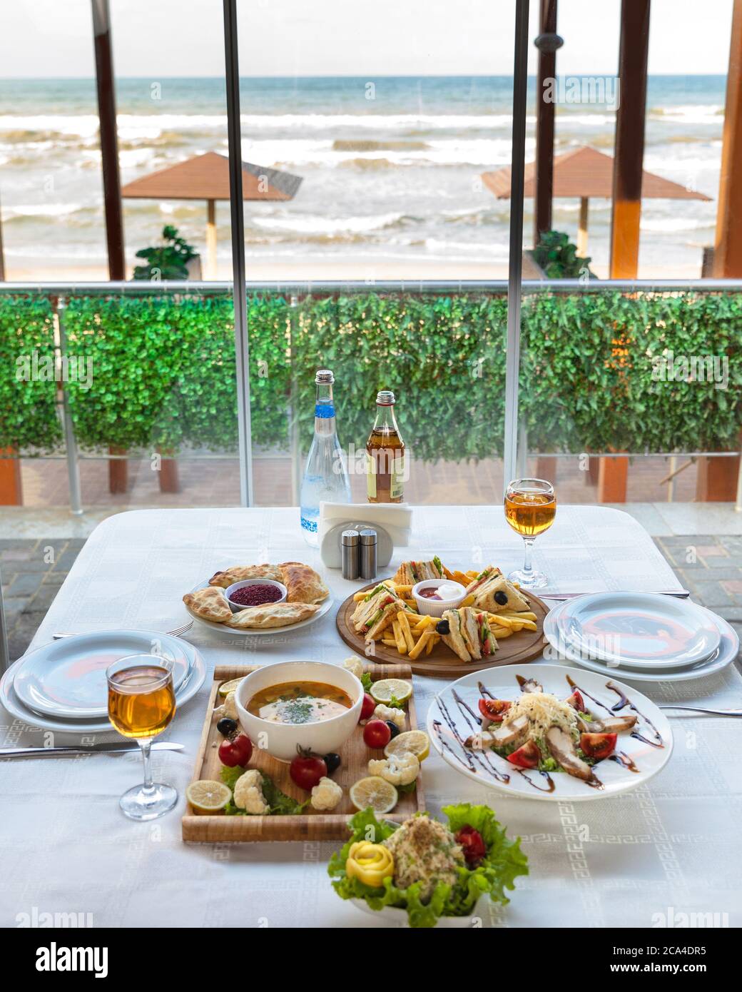 Club sandwich con patatine fritte e zuppa, insalata sul tavolo con vista mare Foto Stock