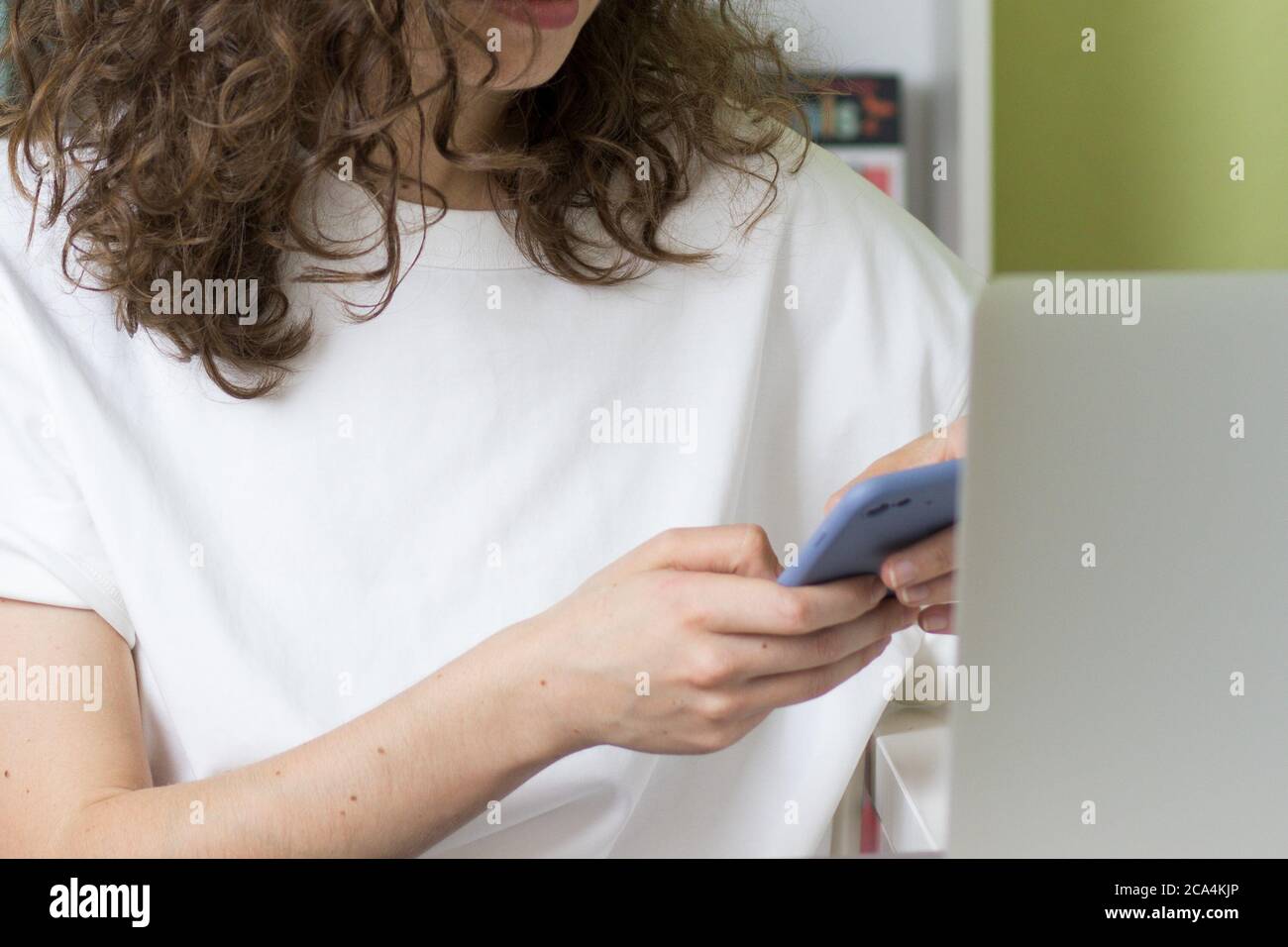 Giovane donna che usa il telefono davanti al computer. Concetto di acquisto online. Spazio di copia. Interni ufficio Foto Stock