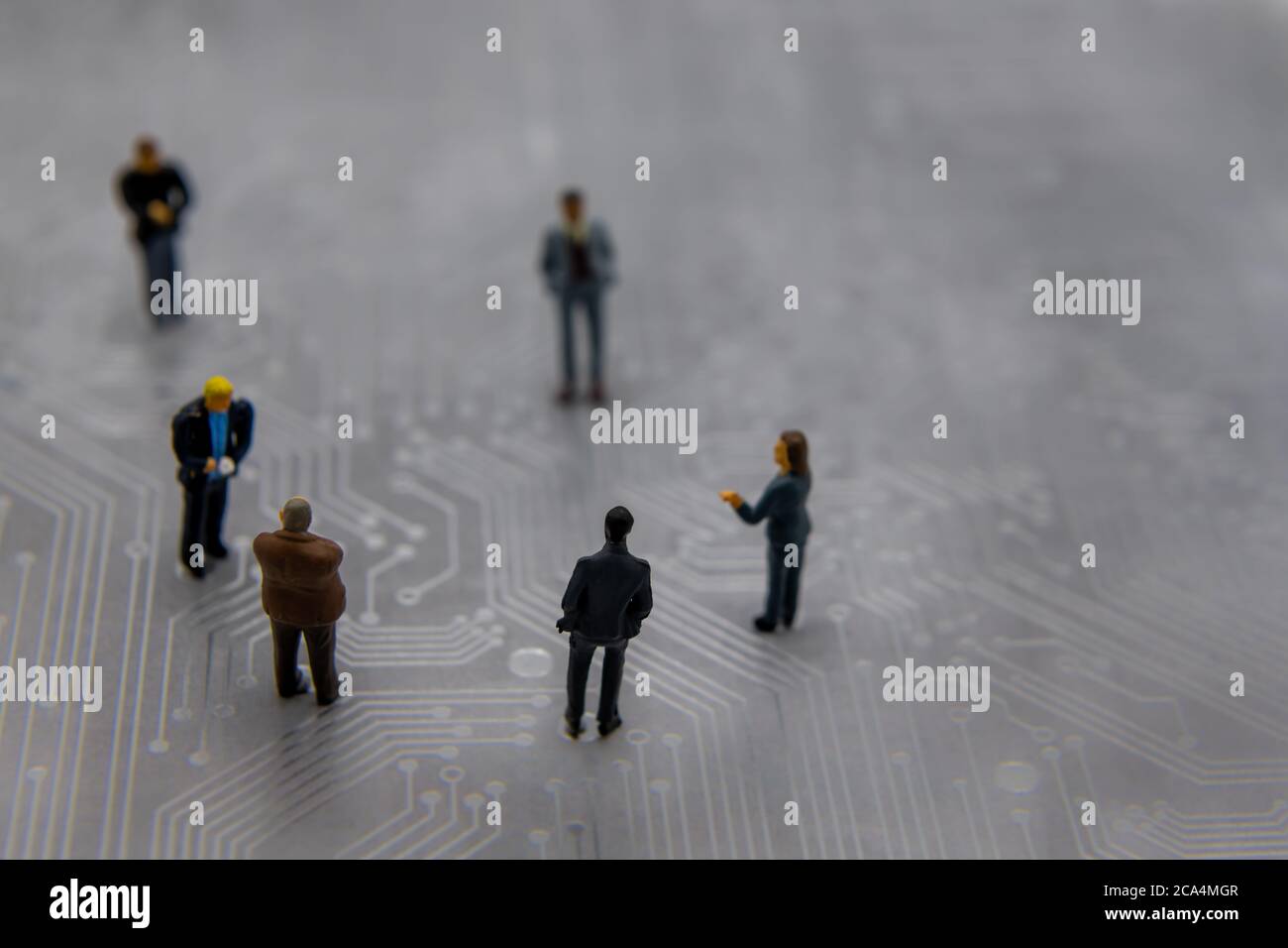 Figurine in miniatura poste come uomini d'affari in una riunione sopra il circuito stampato futuristico astratto, concetto di business futuro Foto Stock