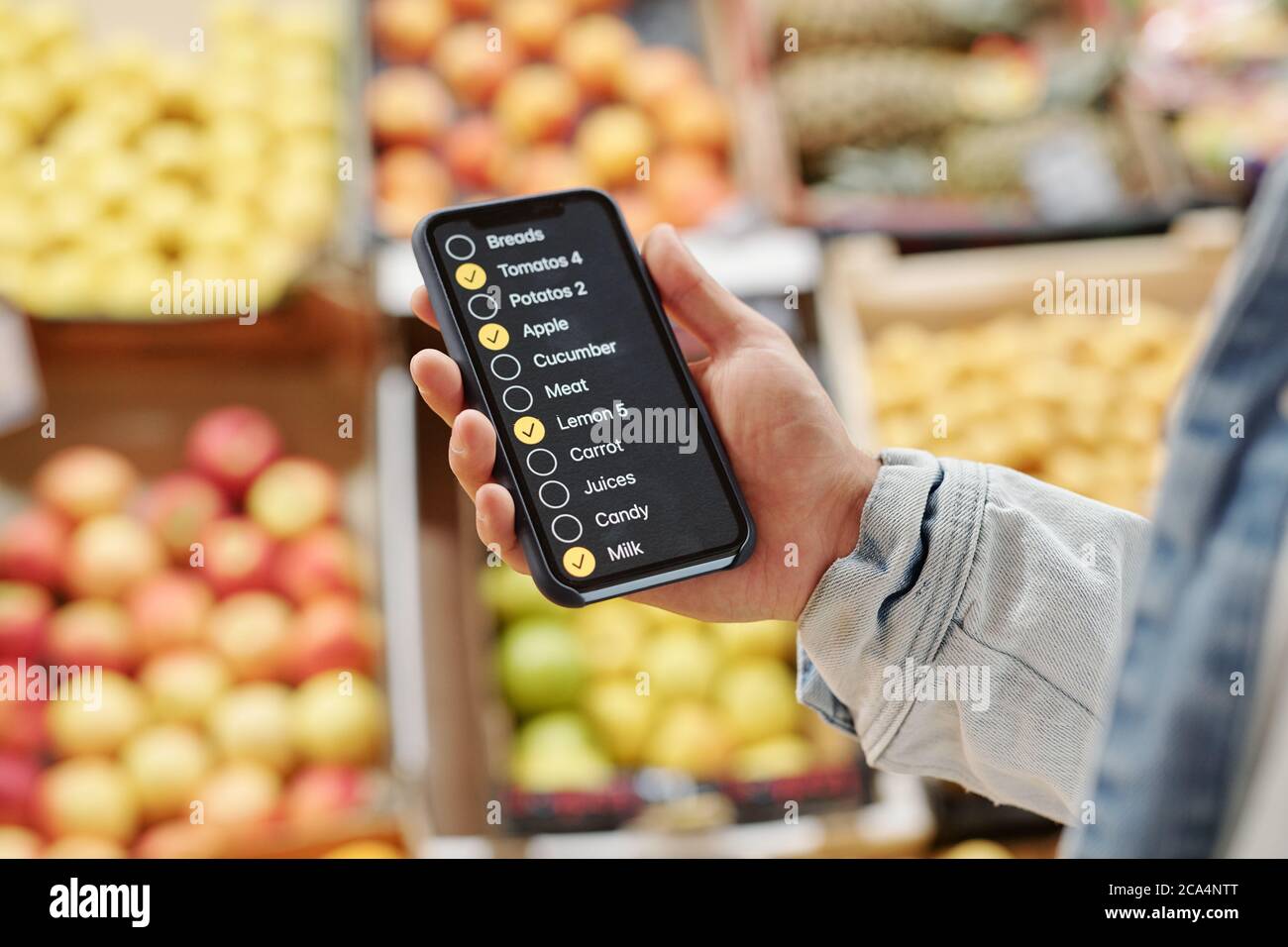 Primo piano di un uomo irriconoscibile utilizzando l'app check-list durante l'acquisto di cibo presso il mercato agricolo Foto Stock