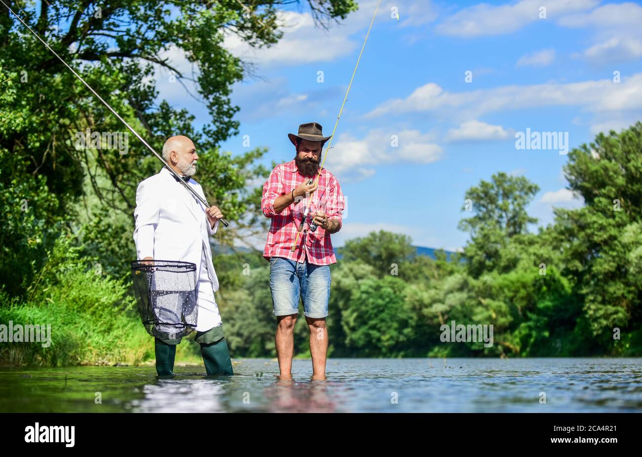 Grande giorno per la pesca. Hobby di uomo d'affari. Pesca di pensione.  Pescatori felici in acqua. Padre in pensione e figlio maturo con barba. Fly  pesca avventure. Amici uomini con canna da