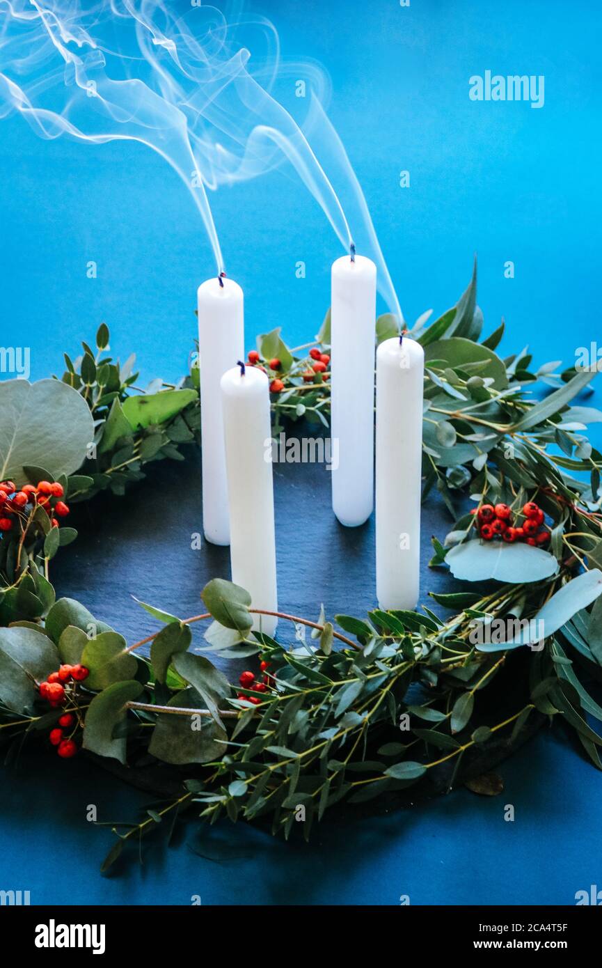 Moderna corona di Natale dell'Avvento con foglie di eucalipto e 4 candele bianche soffiate, ancora fumanti Foto Stock