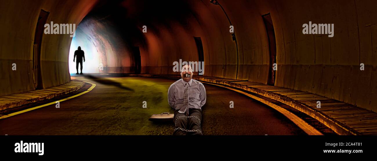Uomo d'affari legato in su in un tunnel con un mostro dentro lo sfondo Foto Stock