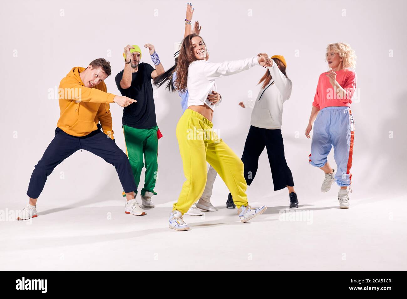 Gruppo di giovani uomini e donne divertenti e felici che ballano hip-hop in  studio su sfondo bianco. Emozioni umane, gioventù, amore e stile di vita  concetto Foto stock - Alamy