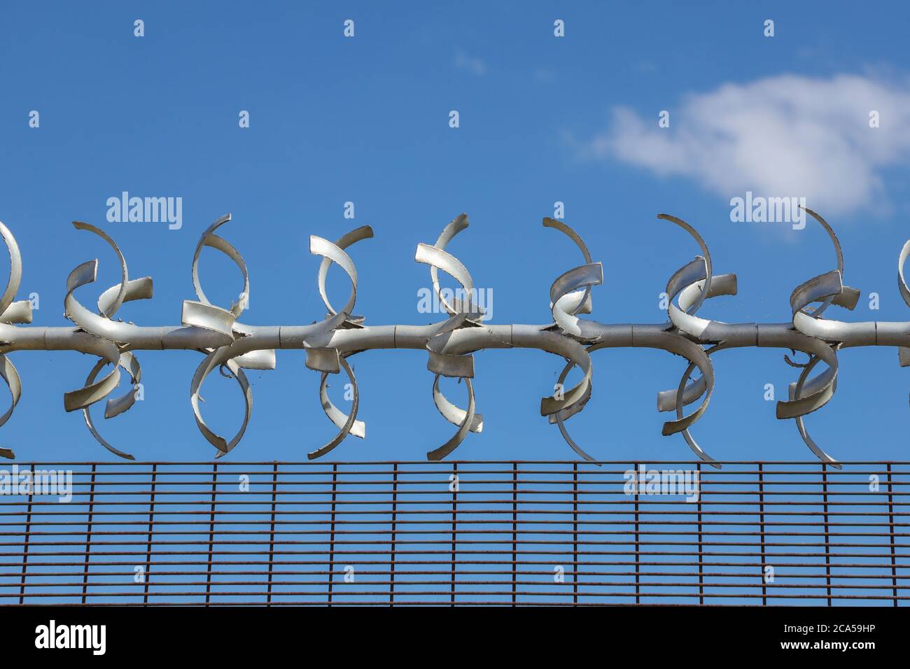 Area riservata. Primo piano di recinzione di sicurezza con filo spinato contro un cielo blu Foto Stock