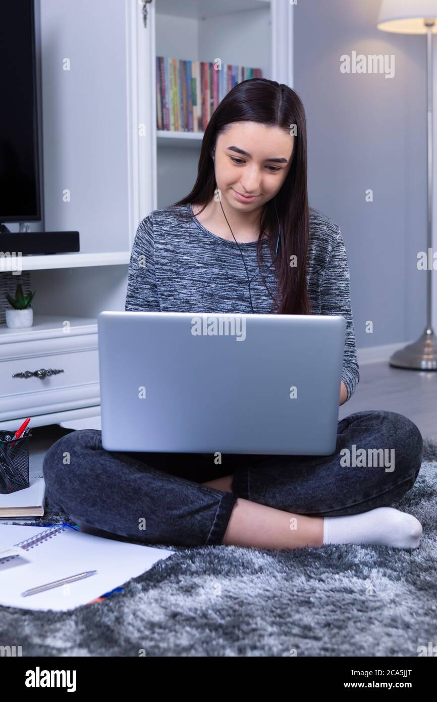 Studentessa con laptop e cuffie che studia online a casa. Concetto di istruzione o di svago. Concentrarsi su di lei. Foto Stock