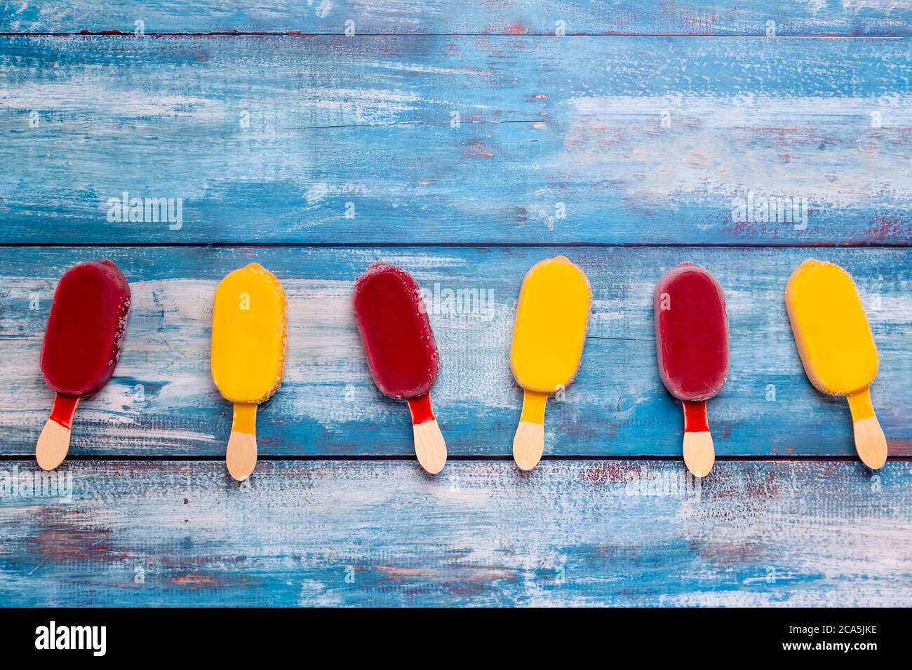 Il bastone di gelato alla frutta sembra fresco da mangiare posto su un legno vintage blu. Foto Stock