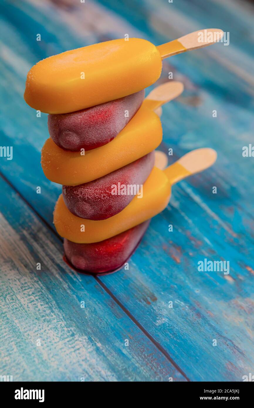 Una pila di bastone di gelato alla frutta sembra fresca da mangiare e si trova su uno sfondo di legno vintage blu. Foto Stock