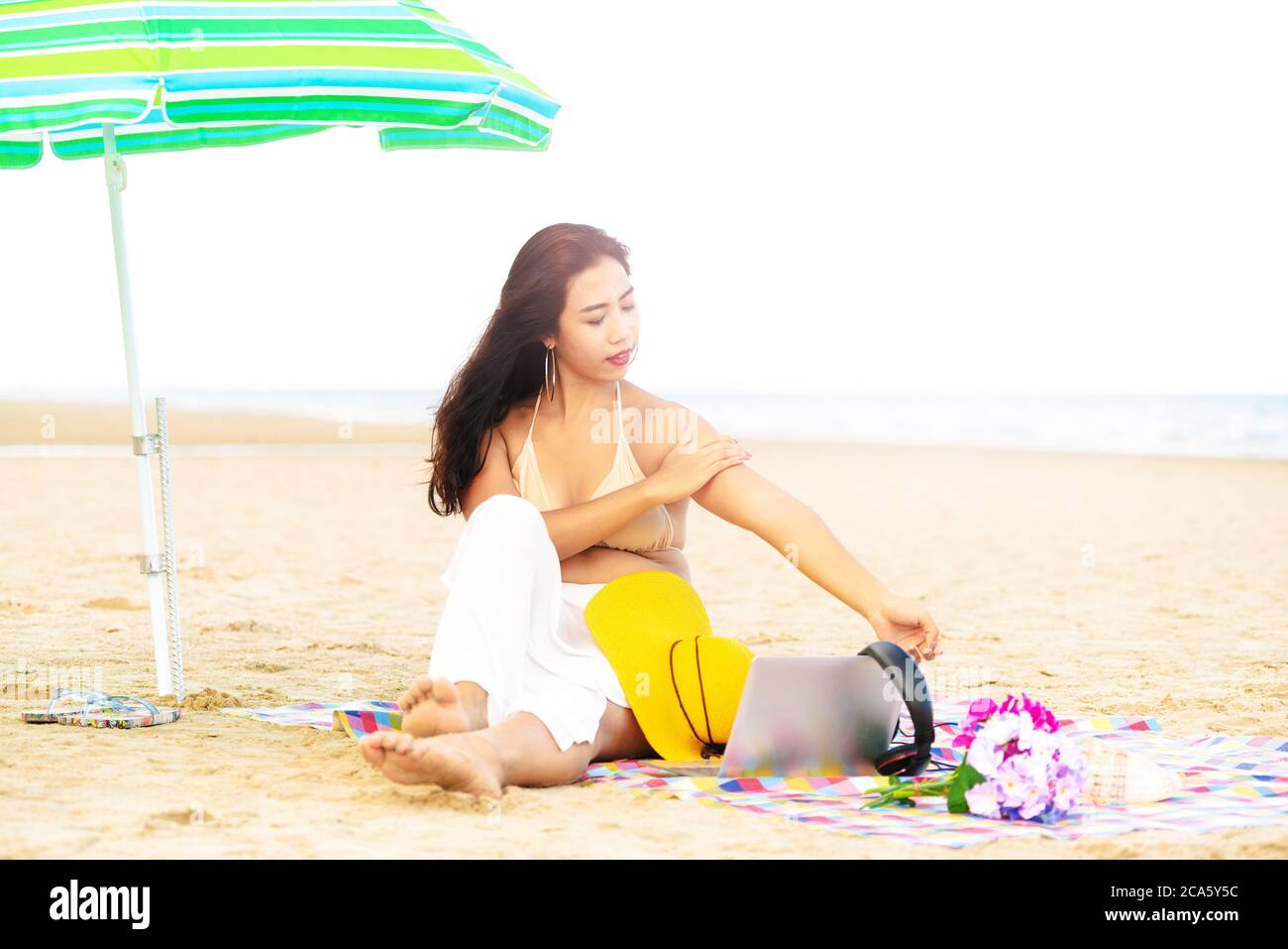 Più giovane donna di taglia seduta sulla spiaggia. Foto Stock