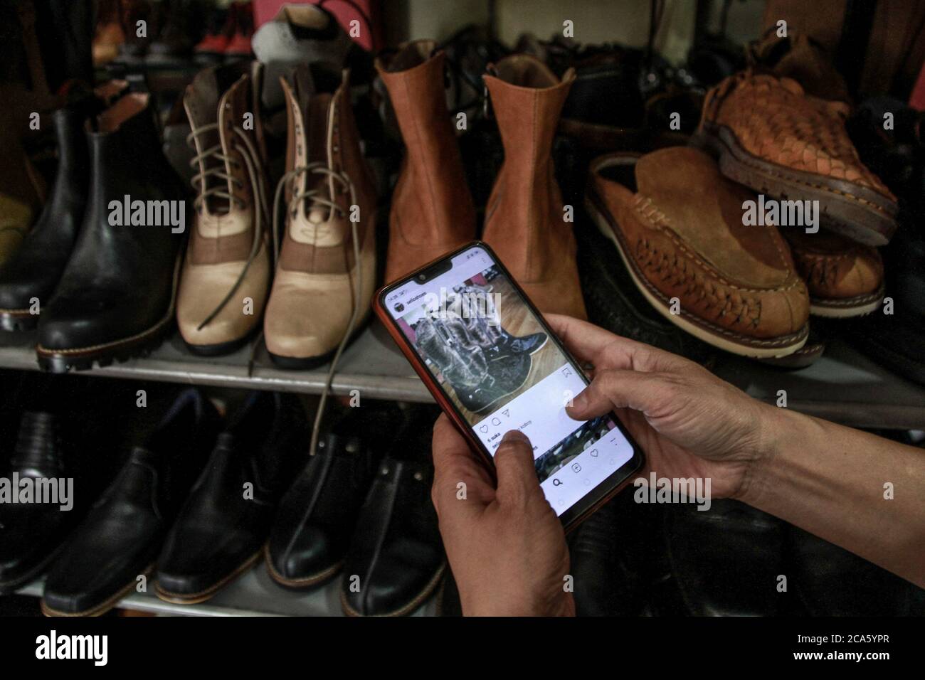 Malang, Indonesia. 04 agosto 2020. Un proprietario del deposito di scarpe prende le foto delle scarpe per vendere in linea in Malang.Rini, il proprietario del deposito di scarpe è costretto a fare la promozione e le vendite in linea durante la pandemia di Covid-19 per mantenere il commercio in funzione anche se il suo reddito è sceso di più di 60 per cento. Credit: SOPA Images Limited/Alamy Live News Foto Stock