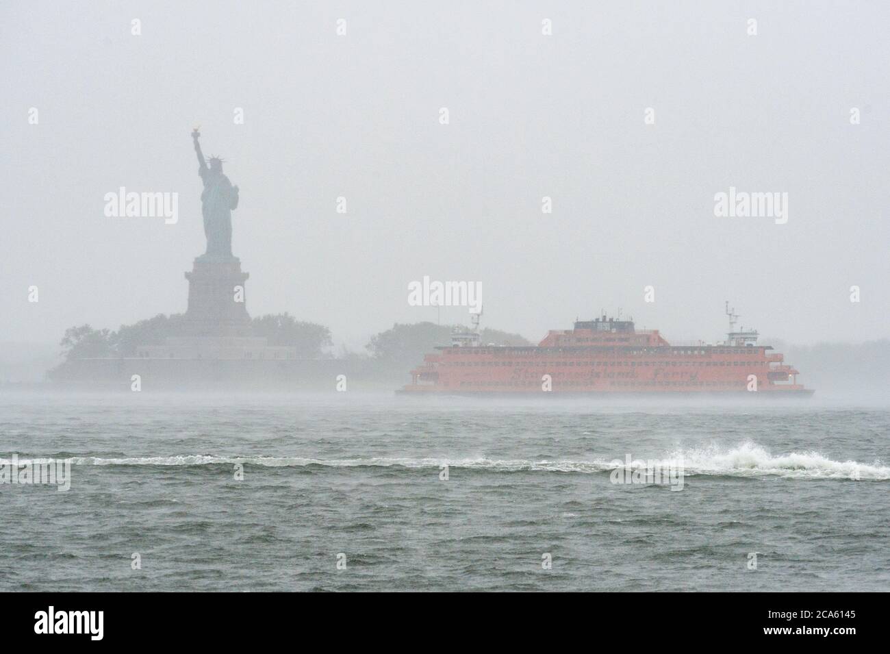 Il traghetto per Staten Island passa dalla Statua della libertà poco prima che il servizio fosse sospeso a causa della tempesta tropicale Isaias il 4 agosto 2020 a New York City. (Foto di Gabriele Holtermann/Sipa USA) Credit: Sipa USA/Alamy Live News Foto Stock