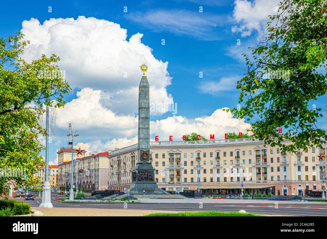 Victory Square nel centro di Minsk con Granite Monumento della Vittoria e lettere rosse sull'edificio leggere immortale, blu cielo bianco nuvole in giorno di sole, Repubblica di Bielorussia Foto Stock