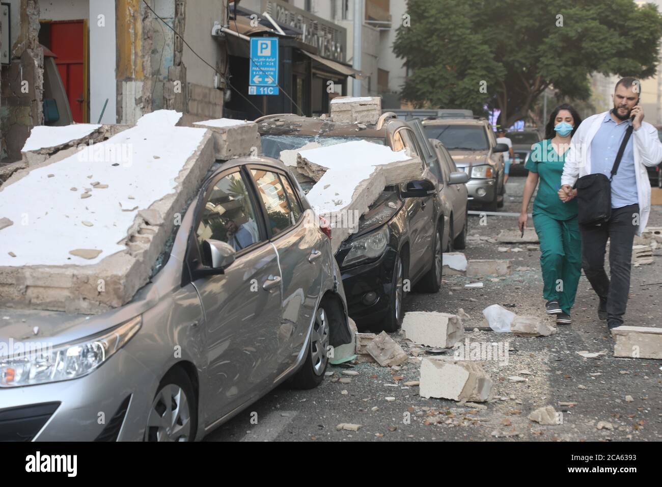 Beirut, Libano. 4 agosto 2020. La gente passa davanti ai veicoli danneggiati dopo l'esplosione a Beirut, Libano, 4 agosto 2020. Le due enormi esplosioni che hanno scosso la capitale libanese Beirut martedì ha lasciato decine di morti e feriti, al-Jadeed canale TV riferito. Credit: Bilal Jawich/Xinhua/Alamy Live News Foto Stock