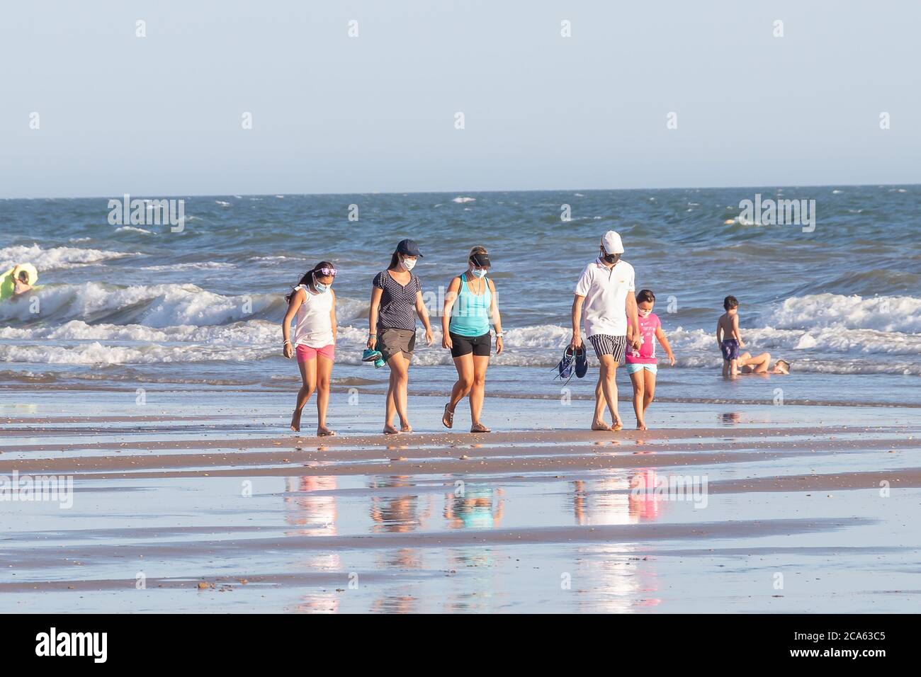 Punta Umbria, Huelva, Spagna - 2 agosto 2020: Una famiglia che cammina sulla spiaggia indossando maschere protettive o mediche. Nuova normalità in Spagna con sociale Foto Stock