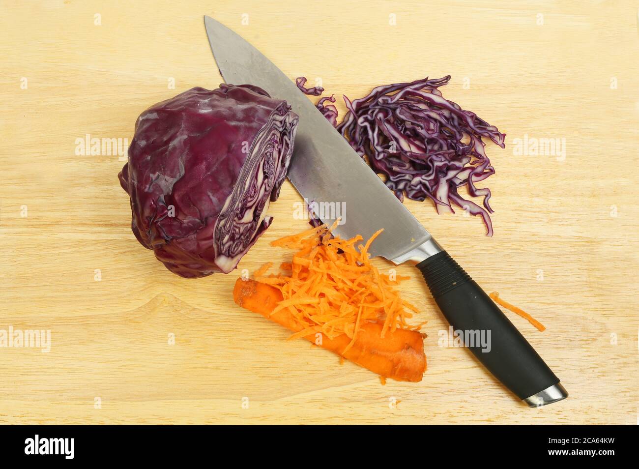 Ingredienti di coleslaw, cavolo rosso e carota con un coltello su una taglierina di legno Foto Stock
