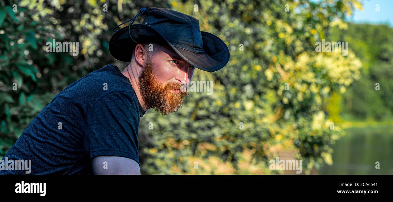 L'uomo beared con il cappello del cowboy guarda in lontananza Foto Stock