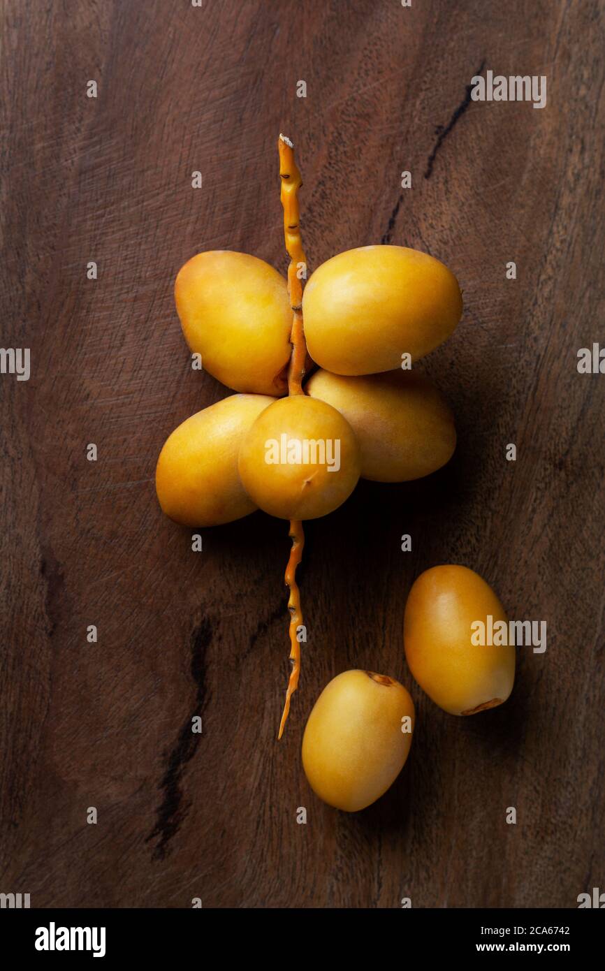 giallo fresco datteri frutta isolato su sfondo di legno Foto Stock