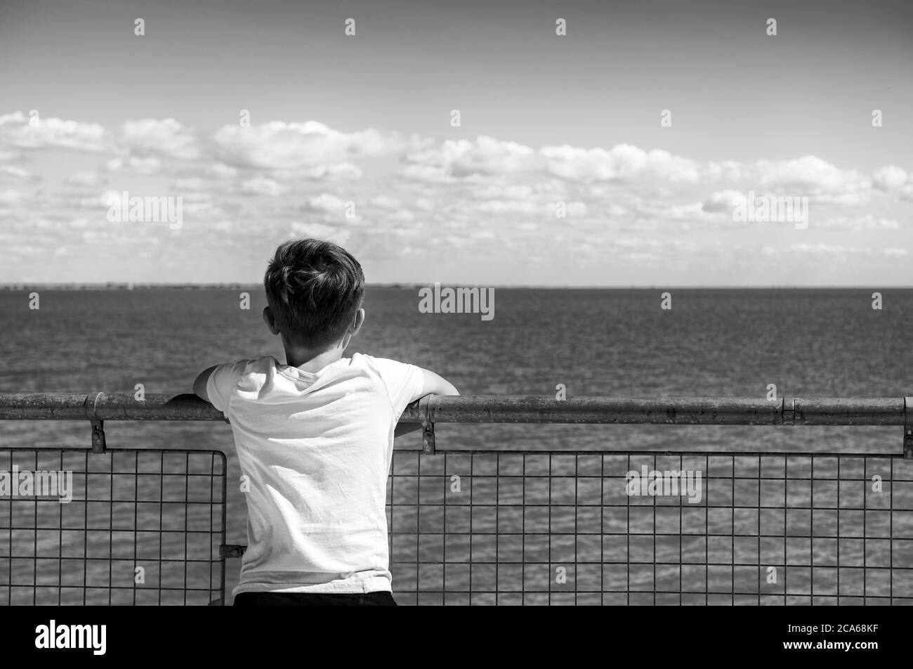 Ragazzo che guarda il mare da dietro Foto Stock