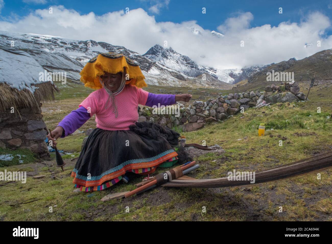 Una donna di quechua nelle alte Ande tesse la lana di alpaca in indumenti, come è stato tradizionalmente fatto per molte generazioni. Foto Stock