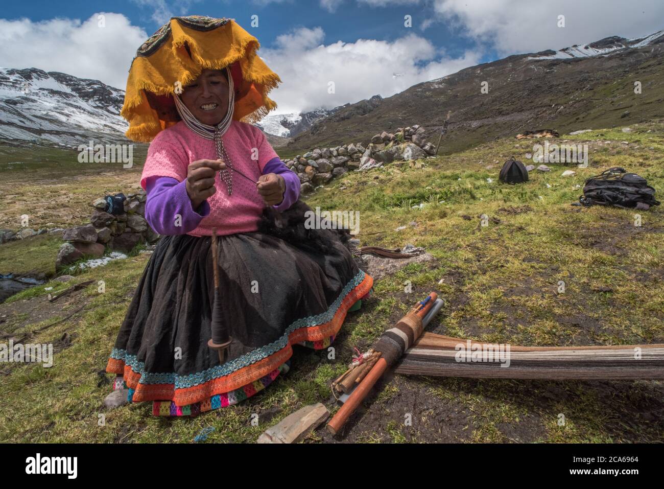 Una donna di quechua nelle alte Ande tesse la lana di alpaca in indumenti, come è stato tradizionalmente fatto per molte generazioni. Foto Stock