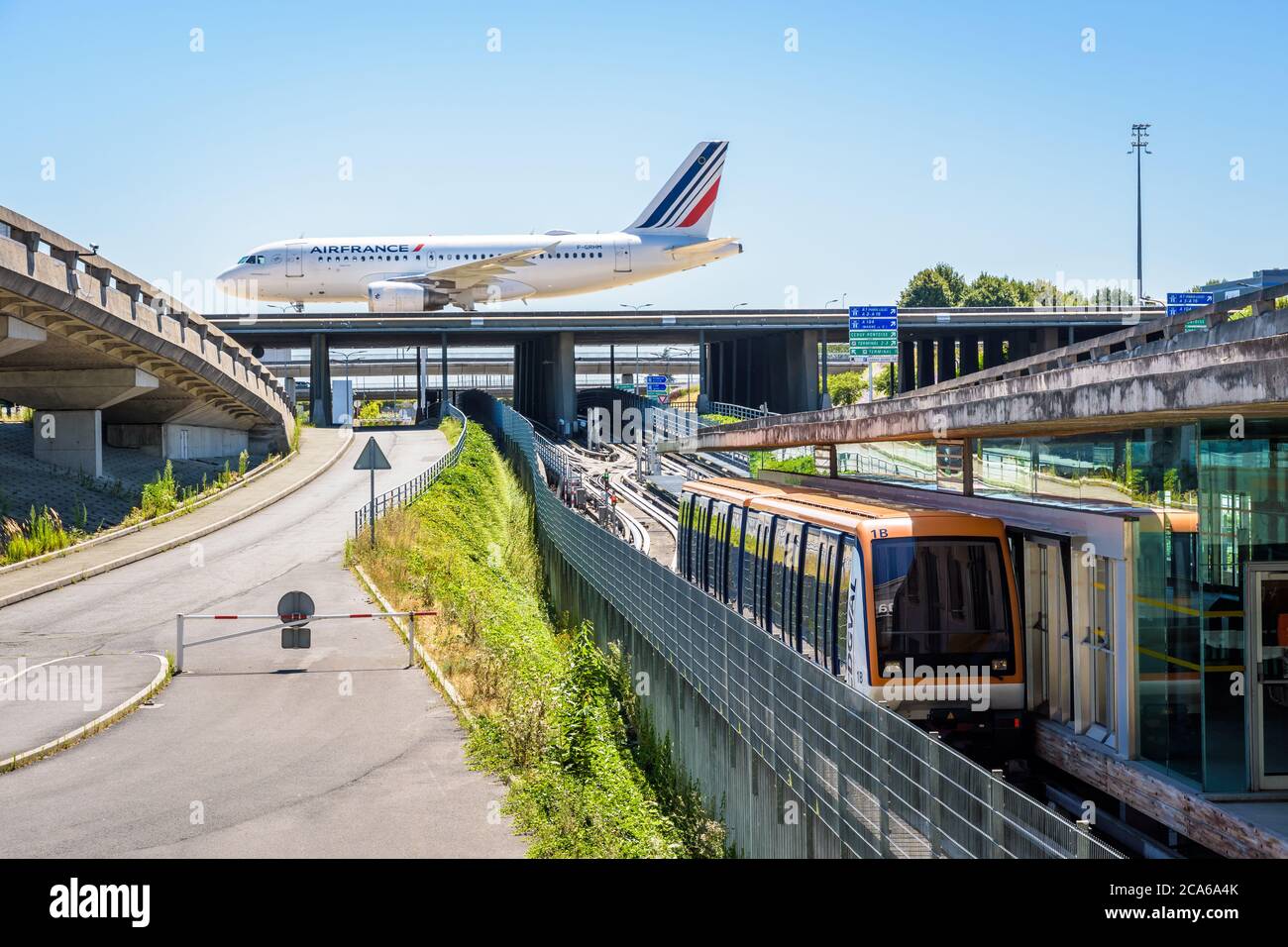 Un aereo di linea sta rotolando su un ponte della Taxiway dell'aeroporto di Parigi-Charles de Gaulle mentre una navetta aeroportuale CDGVAL sta stazionando alla stazione del Terminal 1. Foto Stock