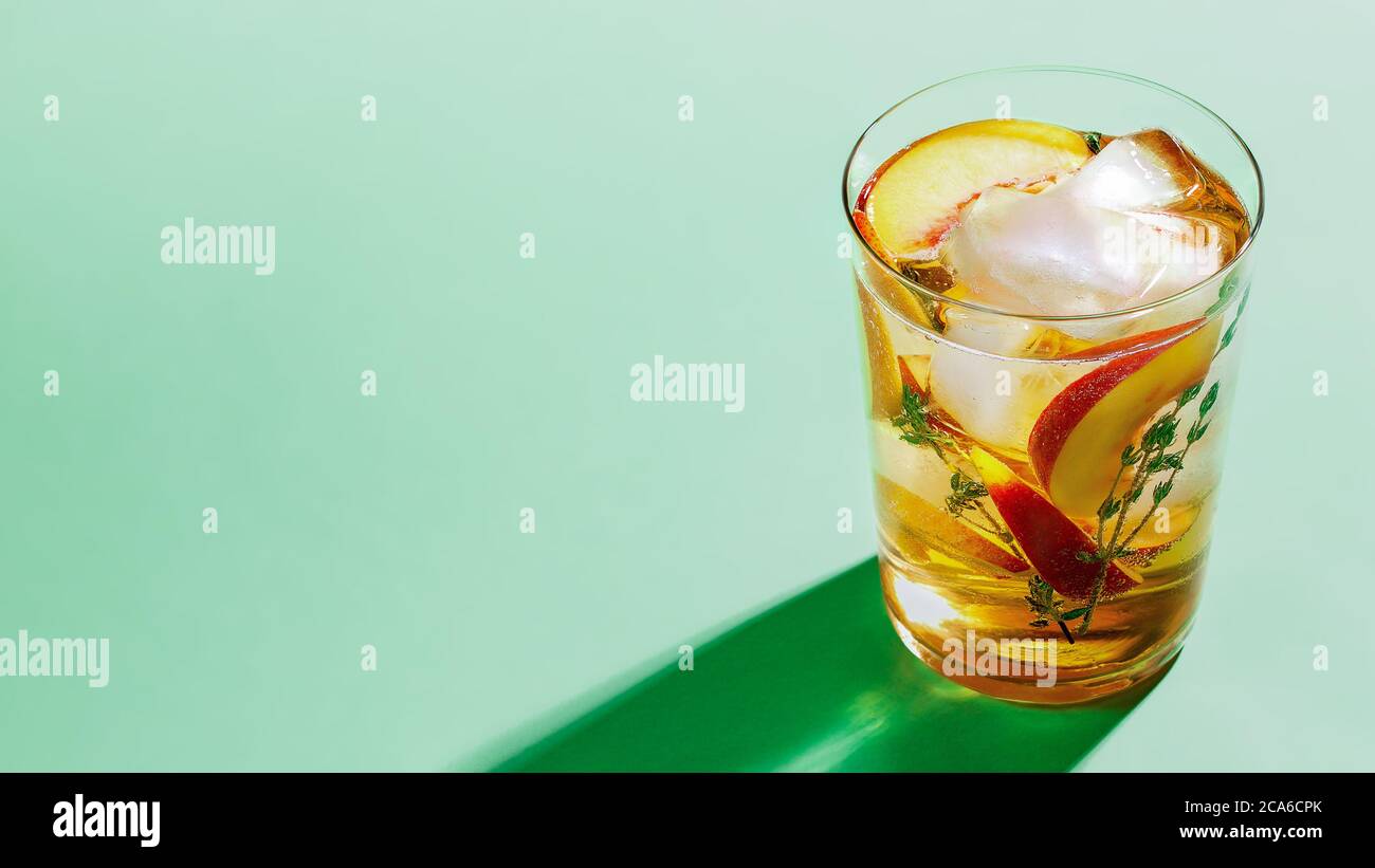 Tè freddo frizzante con timo in vetro su sfondo di carta verde primo piano. Rinfrescante concetto di bevanda analcolica estiva Foto Stock