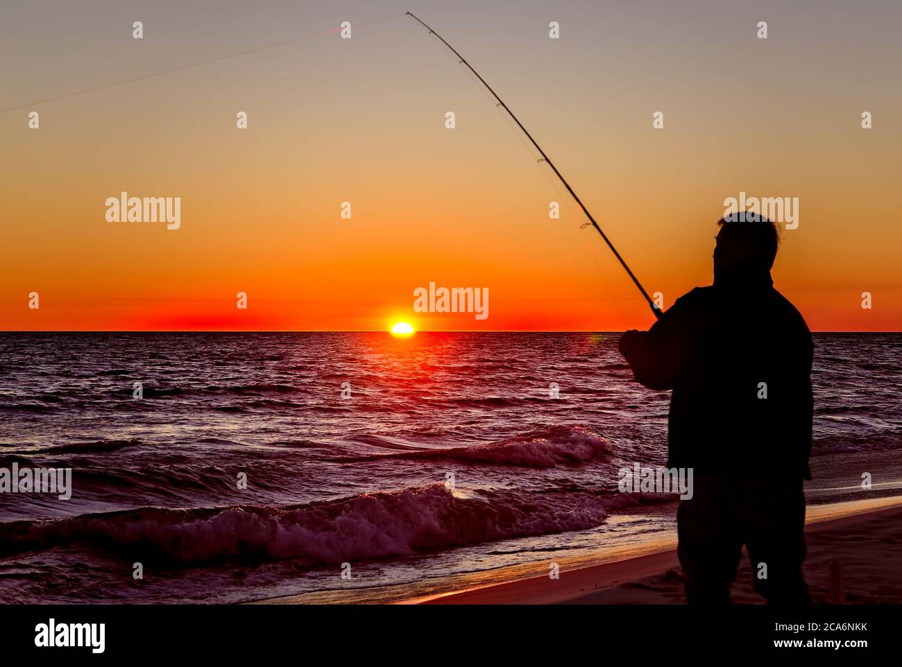 Un uomo è silhouetted mentre pesca al tramonto, 17 dicembre 2013, nell'isola di Dauphin, Alabama. Foto Stock