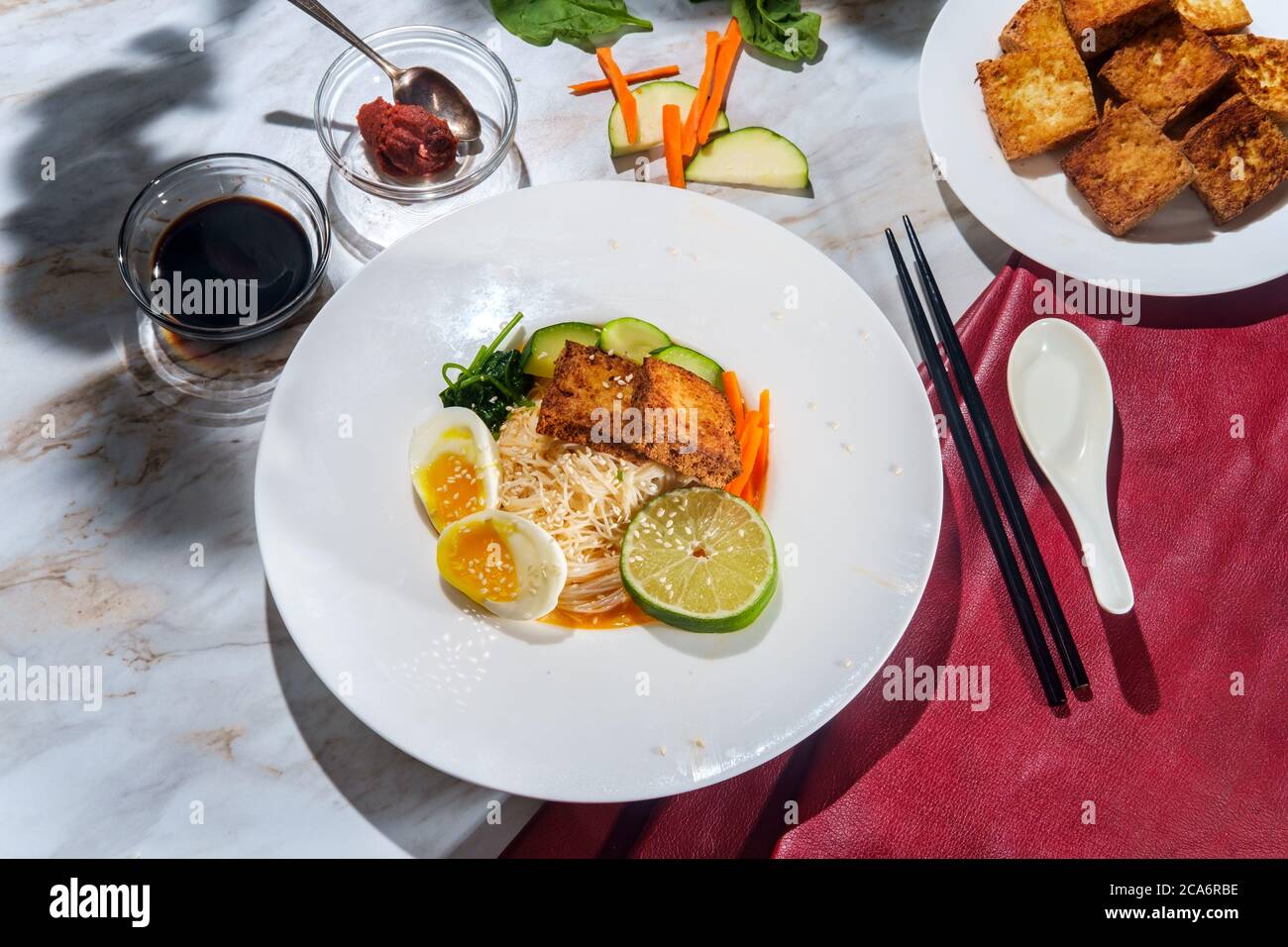 Zuppa di noodle di riso al curry rosso vegetariano thailandese con tofu fritto croccante e uova sode Foto Stock