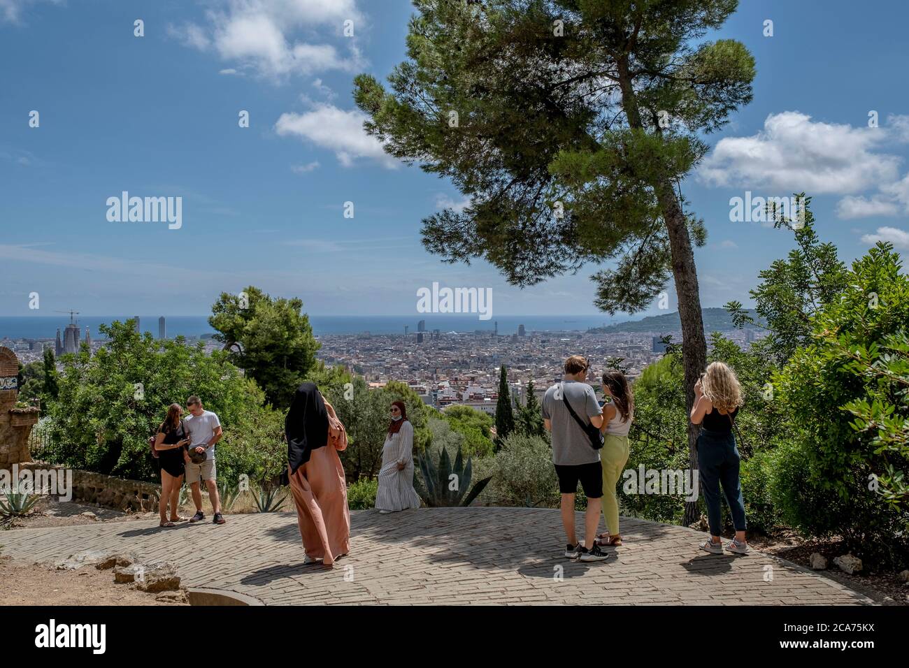 I visitatori sono visti contemplare il Parco Güell e scattare foto da uno dei suoi punti panoramici più alti.nonostante abbiano libero accesso per i residenti di Barcellona durante l'estate, il Parco Güell, uno degli spazi più visitati della città di Barcellona, Ha una scarsa presenza di turisti e visitatori a causa di focolai di contagio Covid-19. Foto Stock