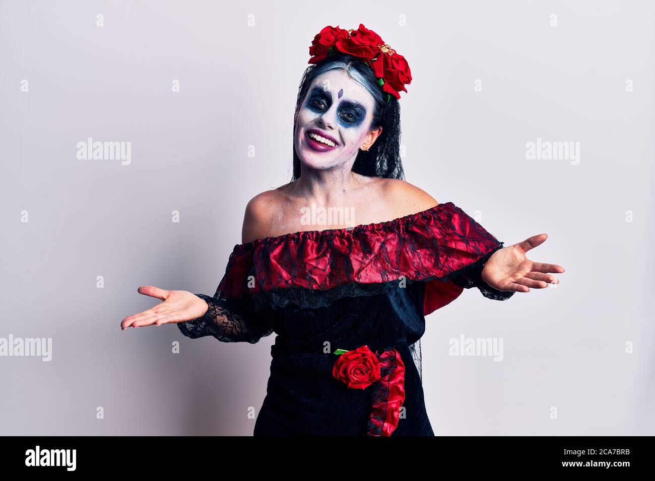 Giovane donna che indossa il giorno messicano del trucco morto sorridente allegro a braccia aperte come cordiale benvenuto, positivi e fiduciosi saluti Foto Stock