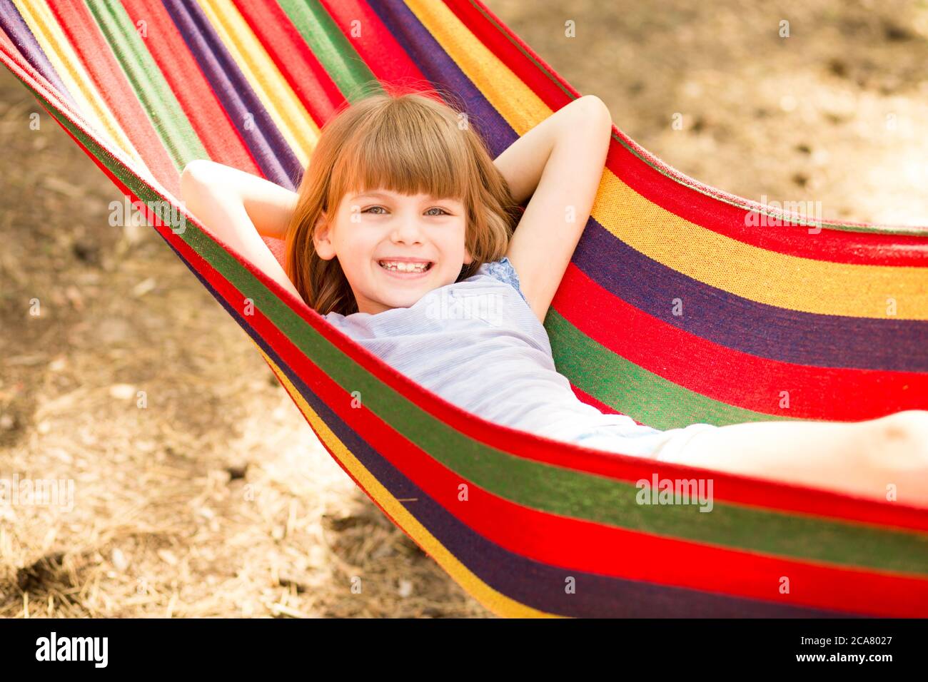 Felice bella bambina che si rilassa in amaca colorata nella foresta estiva. Vacanze estive Foto Stock