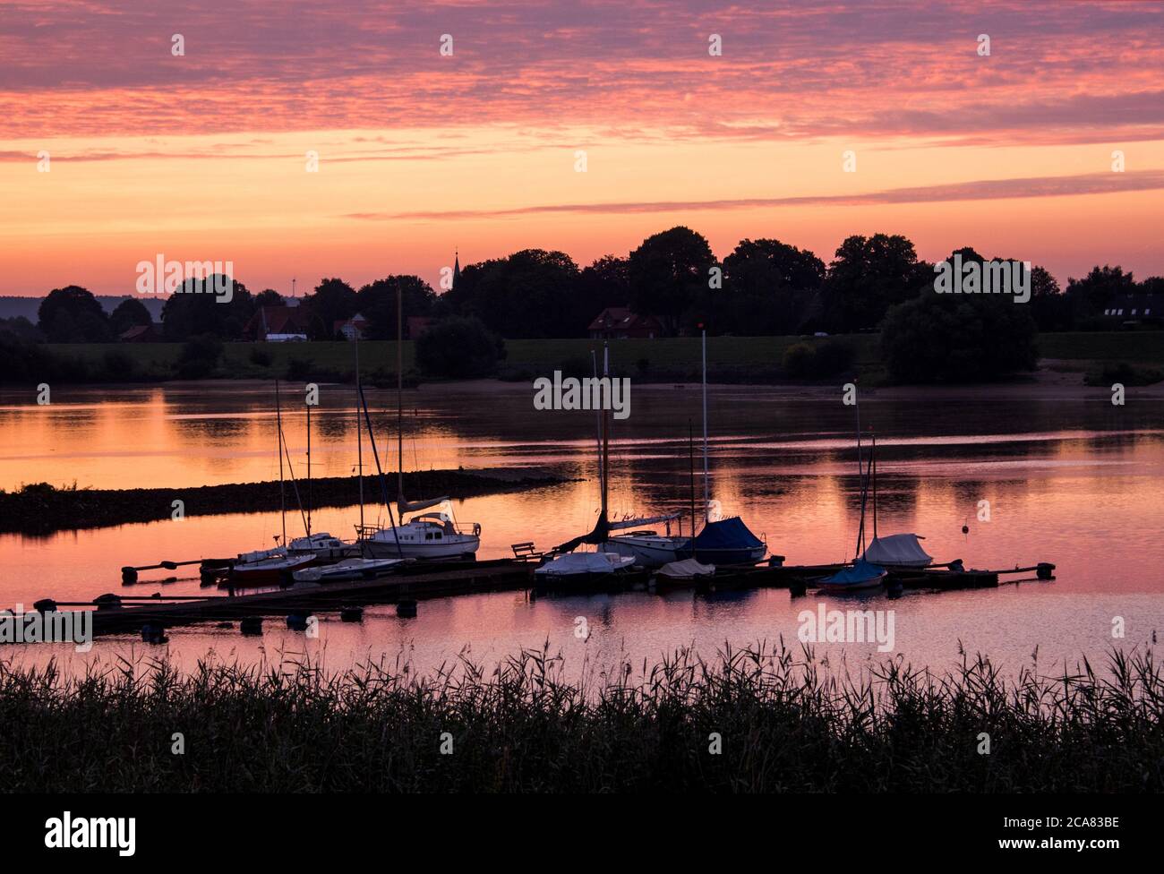 Amburgo, Germania. 05 agosto 2020. Le barche sono ormeggiate nel quartiere di Neuengamme poco prima dell'alba di fronte al cielo luminoso presso un molo sull'Elba. Credit: Daniel Bockwoldt/dpa/Alamy Live News Foto Stock