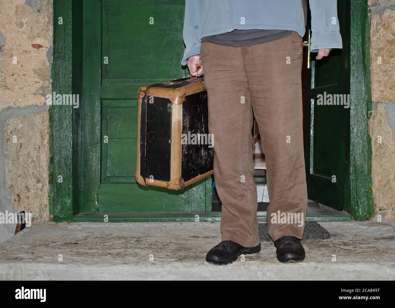 Parte centrale dell'uomo in piedi nella porta con valigia vintage Foto Stock