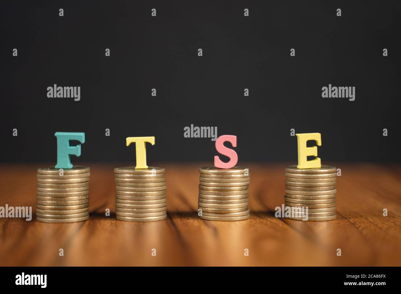 Concetto di FTSE o Financial Times Stock Exchange che mostra con monete e lettere su sfondo nero. Foto Stock