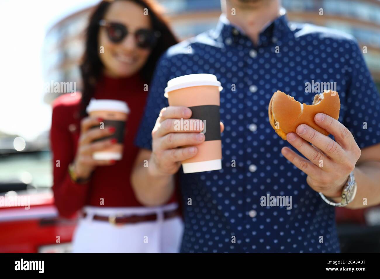 L'uomo e la donna tengono caffè e hamburger Foto Stock