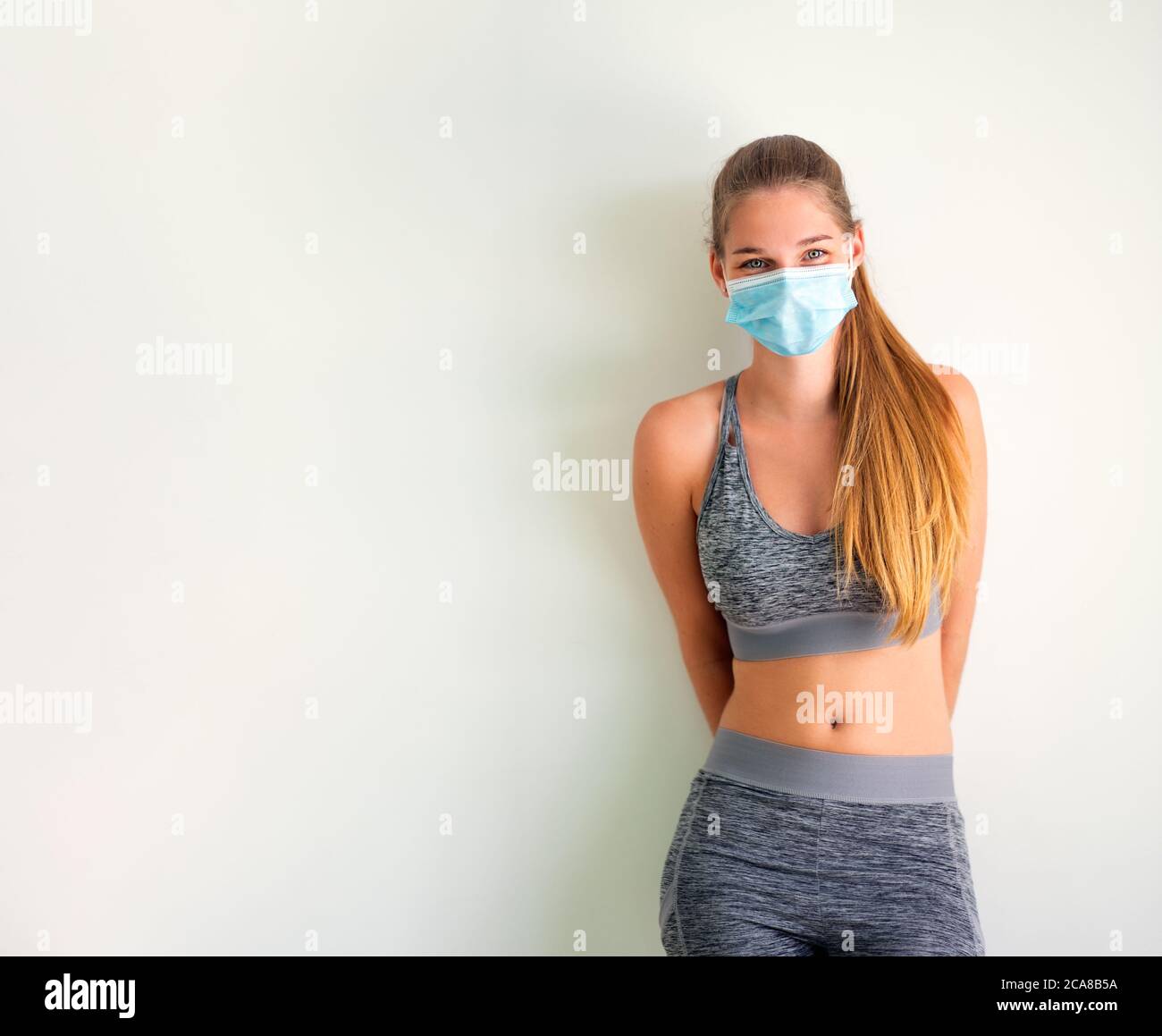 ritratto di una giovane donna sportiva con maschera medica - donna in abbigliamento sportivo con maschera protettiva contro il virus covid Foto Stock