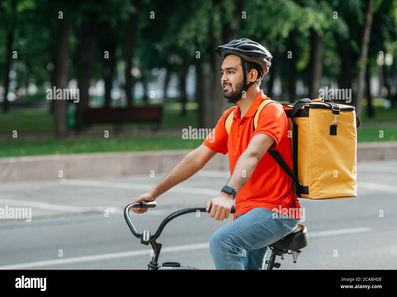 Lavori all'aperto. Vista laterale di un uomo in bicicletta attraverso la città Foto Stock
