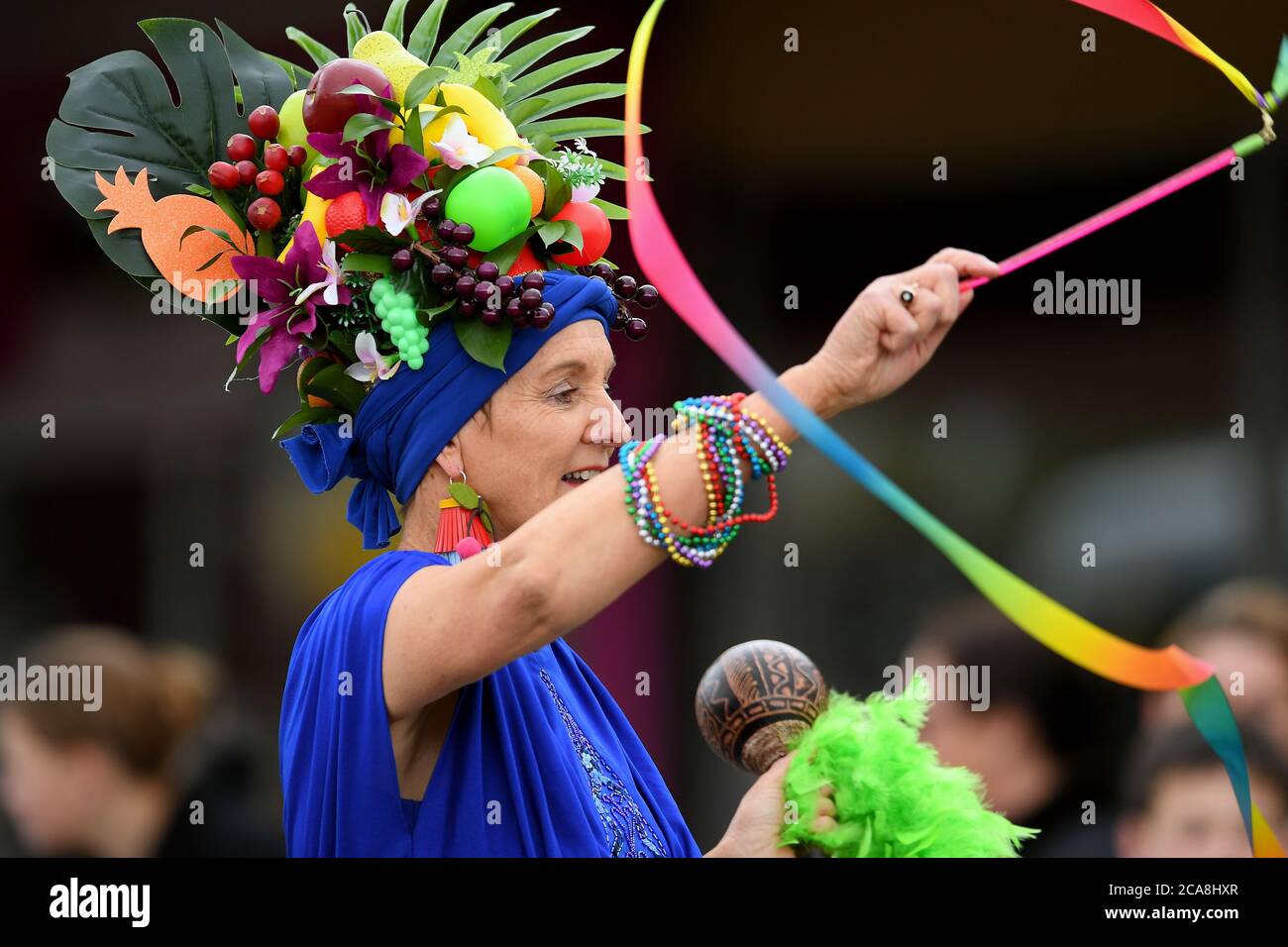 Benalla Festival 2019. Una donna dai colori vivaci con frutta esotica sulla testa Foto Stock