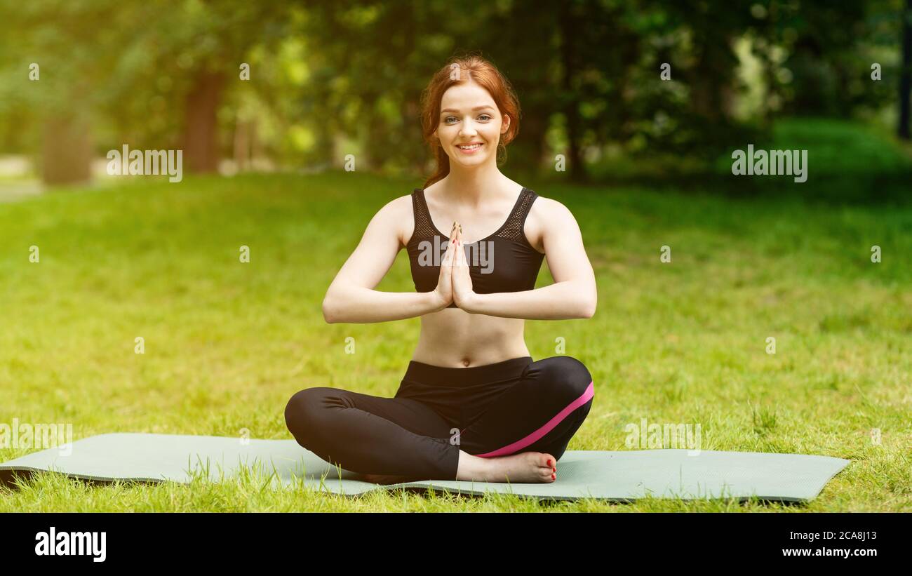 Allegra donna caucasica che fa gesto a namaste durante la sua meditazione yoga all'aperto Foto Stock