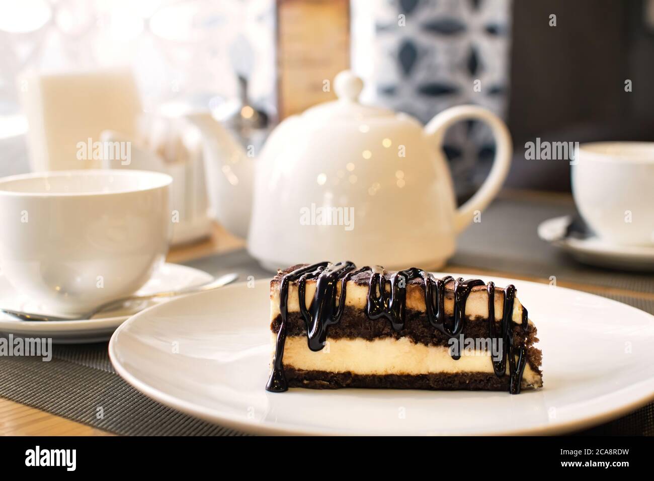 Fetta di gustoso tiramisù sul piatto bianco sul tavolo nel caffè. Dolce o torta tradizionale di biscotti italiani. Foto Stock