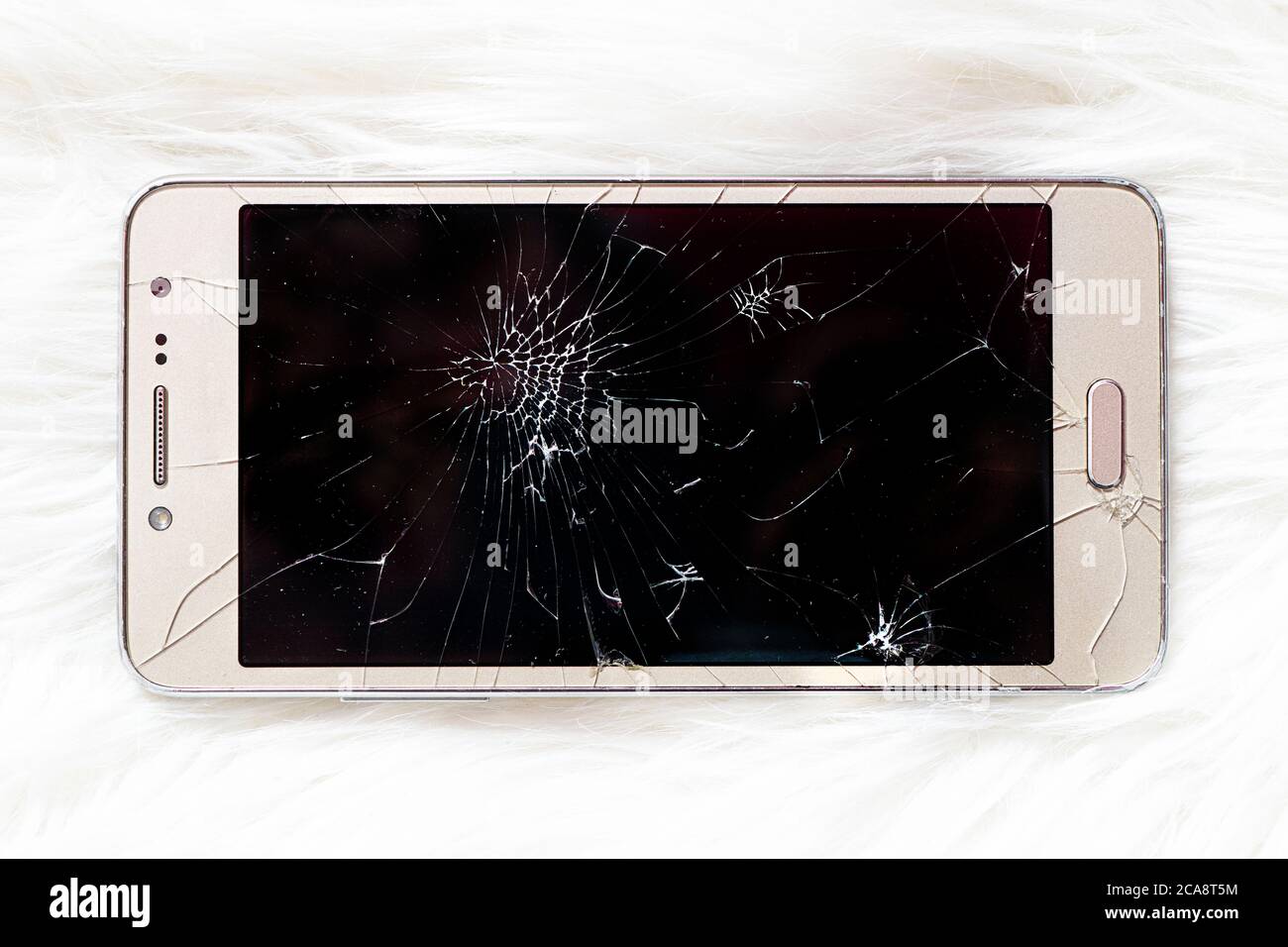 Un vecchio iPhone con uno schermo nero rotto su sfondo bianco. Foto Stock