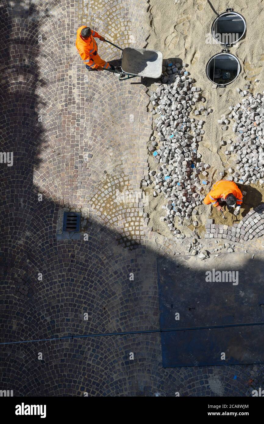 Vista aerea di due operai che riplavano una strada con blocchi di granito, Alba, Cuneo, Piemonte, Italia Foto Stock