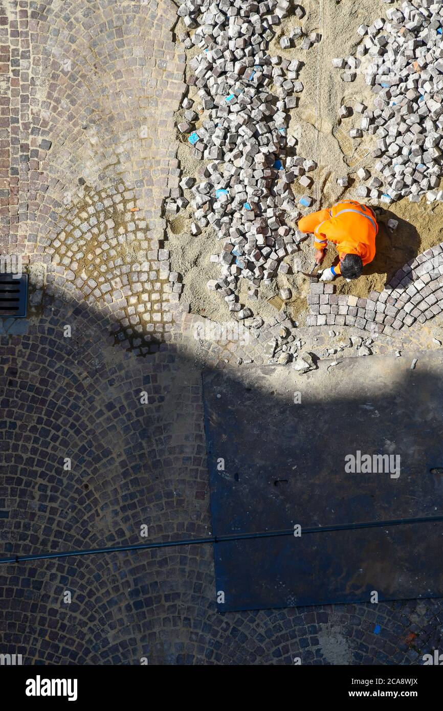 Vista aerea di un operaio che ripavera una strada con blocchi di granito, Alba, Cuneo, Piemonte, Italia Foto Stock