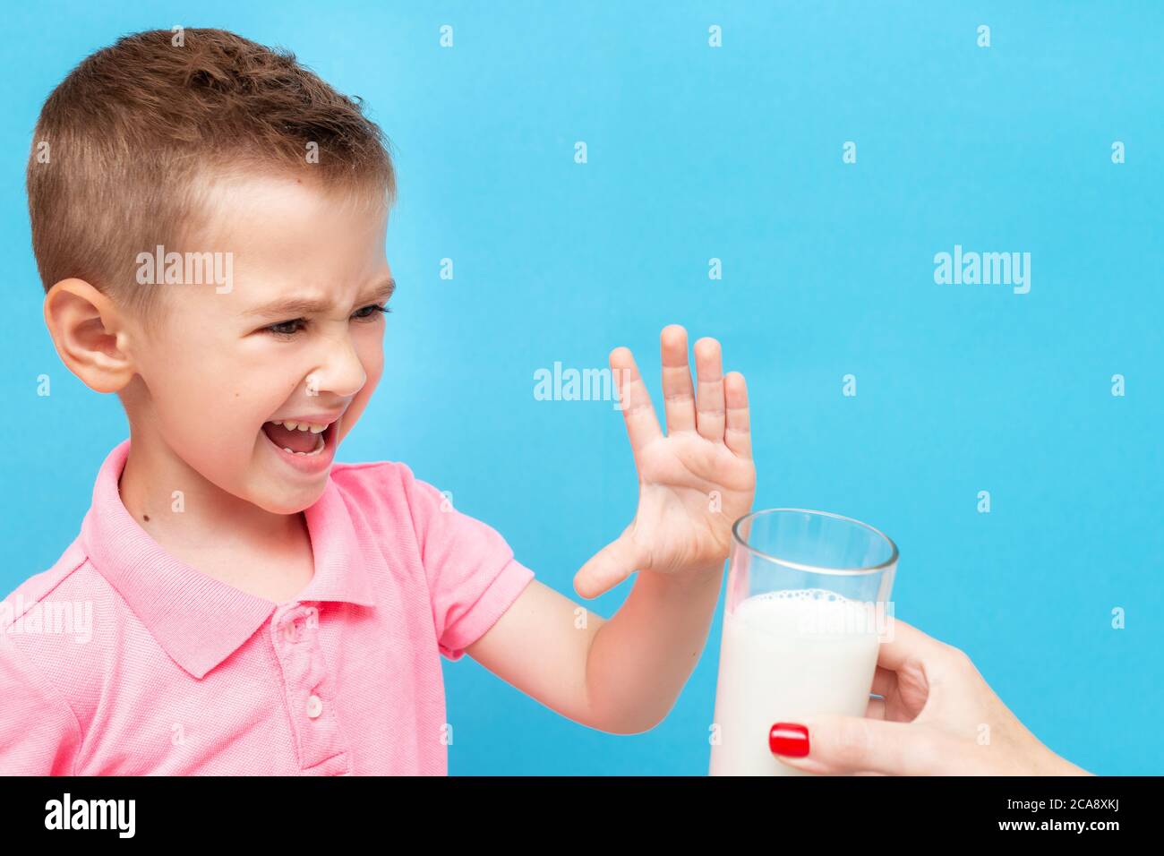 Triste e pericoloso bambino che si rifiuta di bere latte mostrando gesto di stop Foto Stock